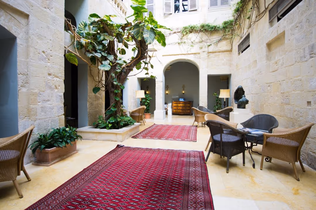 The limestone atrium at The Xara Palace, with a planted courtyard and seating beneath tall windows
